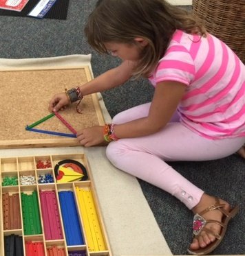 A student working with Montessori materials on the classroom floor