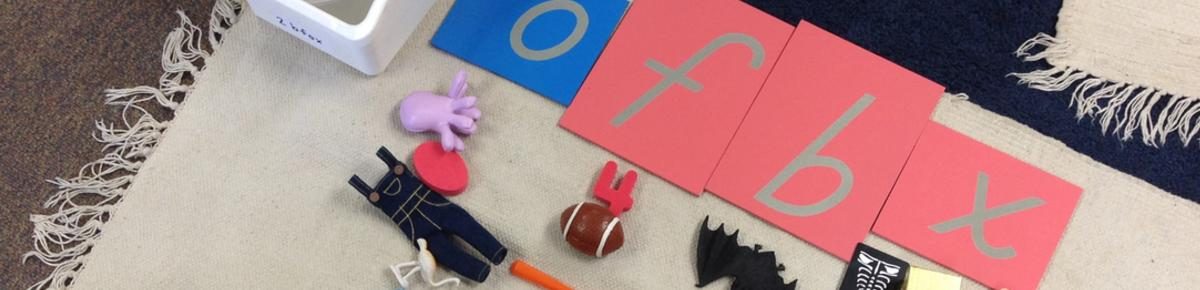 Montessori sandpaper letters and phonetic objects on a classroom rug