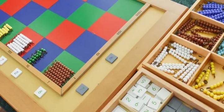 Montessori math materials — a colored checkerboard board with bead chains and number tiles