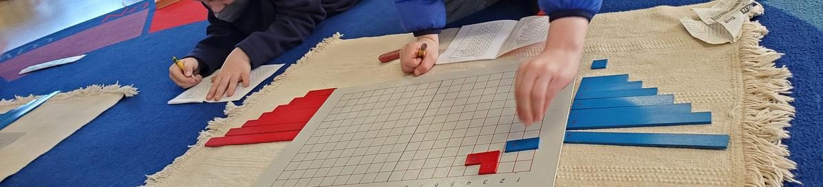 Students working with Montessori materials on a classroom rug